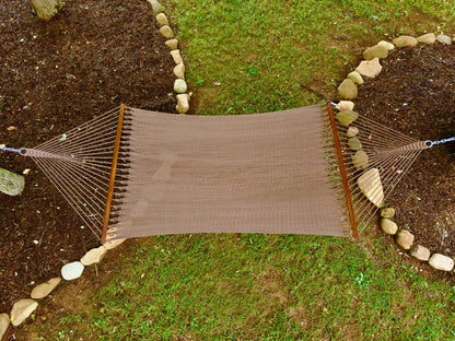 Overhead view of a mocha Island Oasis hammock hung between two stone-edged garden beds