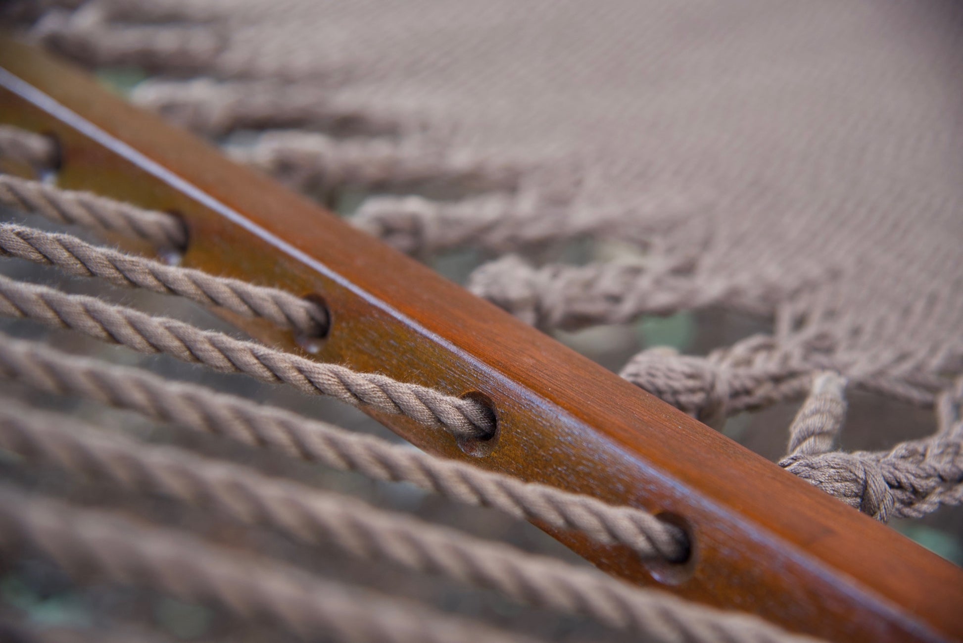 Polyester cords threaded through the drilled hardwood spreader bar of a mocha Island Oasis hammock