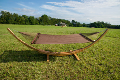 Mocha Island Oasis hammock hanging on the Wood Arc Hammock Stand in a pasture with a barn behind
