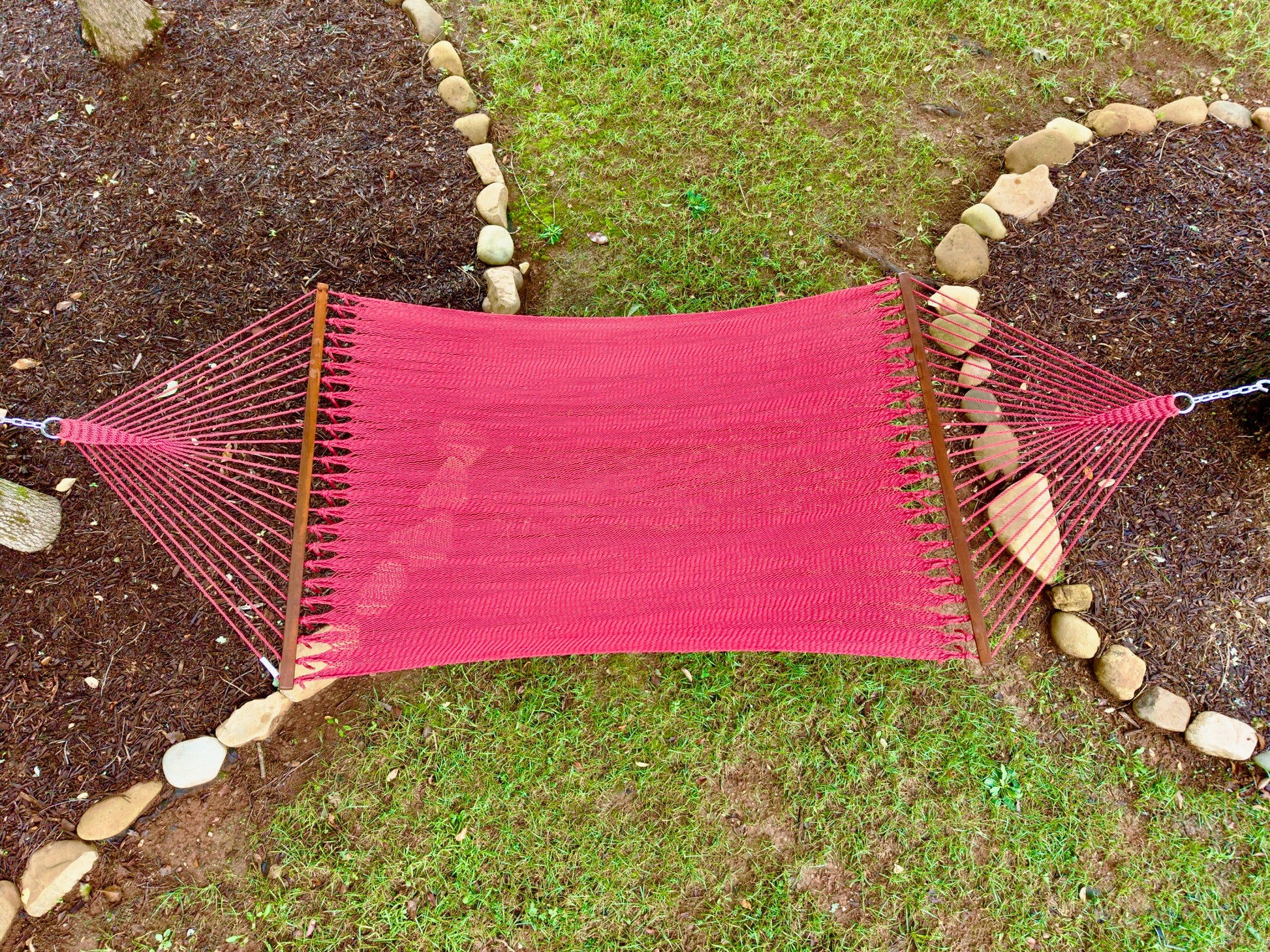 Overhead view of a red Island Oasis hammock hung between two stone-edged garden beds