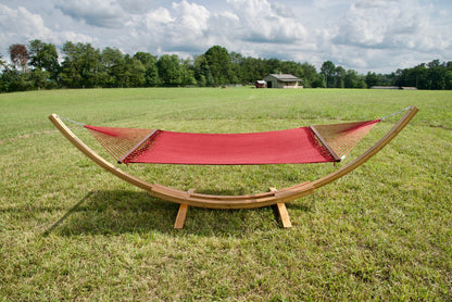 Red Island Oasis hammock hanging on the Wood Arc Hammock Stand in a pasture with a barn behind