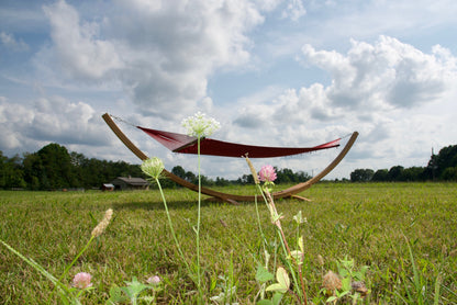 Red Island Oasis hammock on the Wood Arc Hammock Stand seen low through wildflowers in a grassy field