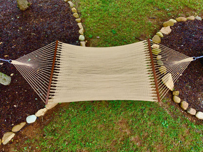 Overhead view of a tan Island Oasis hammock hung between two stone-edged garden beds