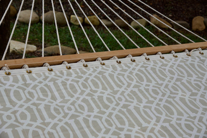Polyester end cords fanning from the wood spreader bar of a beige pattern Island Tranquility hammock