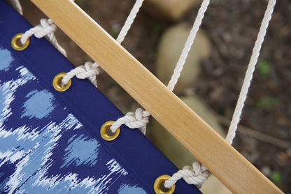 Brass roll-rimmed grommets and knotted polyester end cords along the wood spreader bar of a blue wave Island Tranquility hammock