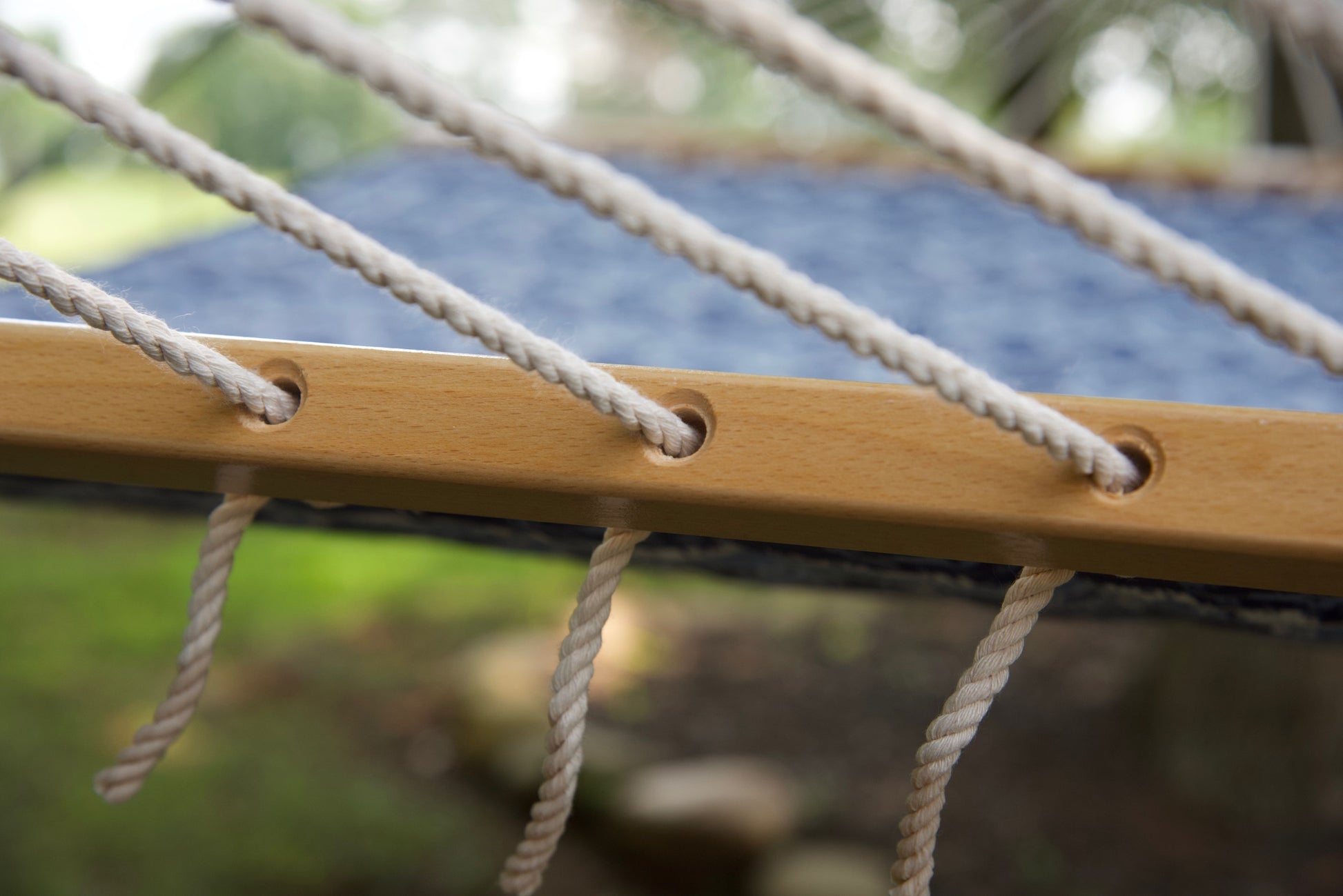 Polyester end cords threaded through the drilled wood spreader bar of a blue wave Island Tranquility hammock