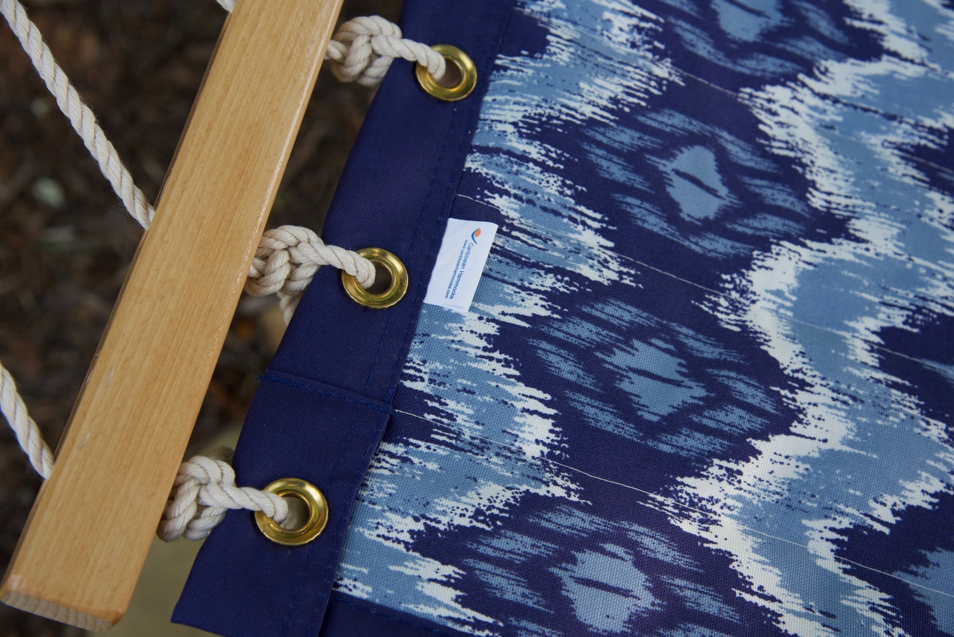 Brass roll-rimmed grommets and polyester end cords on the reinforced edge of a blue wave Island Tranquility hammock