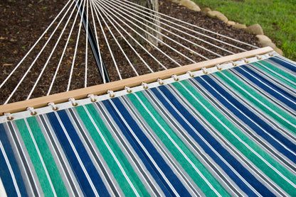 Polyester end cords fanning from the wood spreader bar of a green and blue stripe Island Tranquility hammock