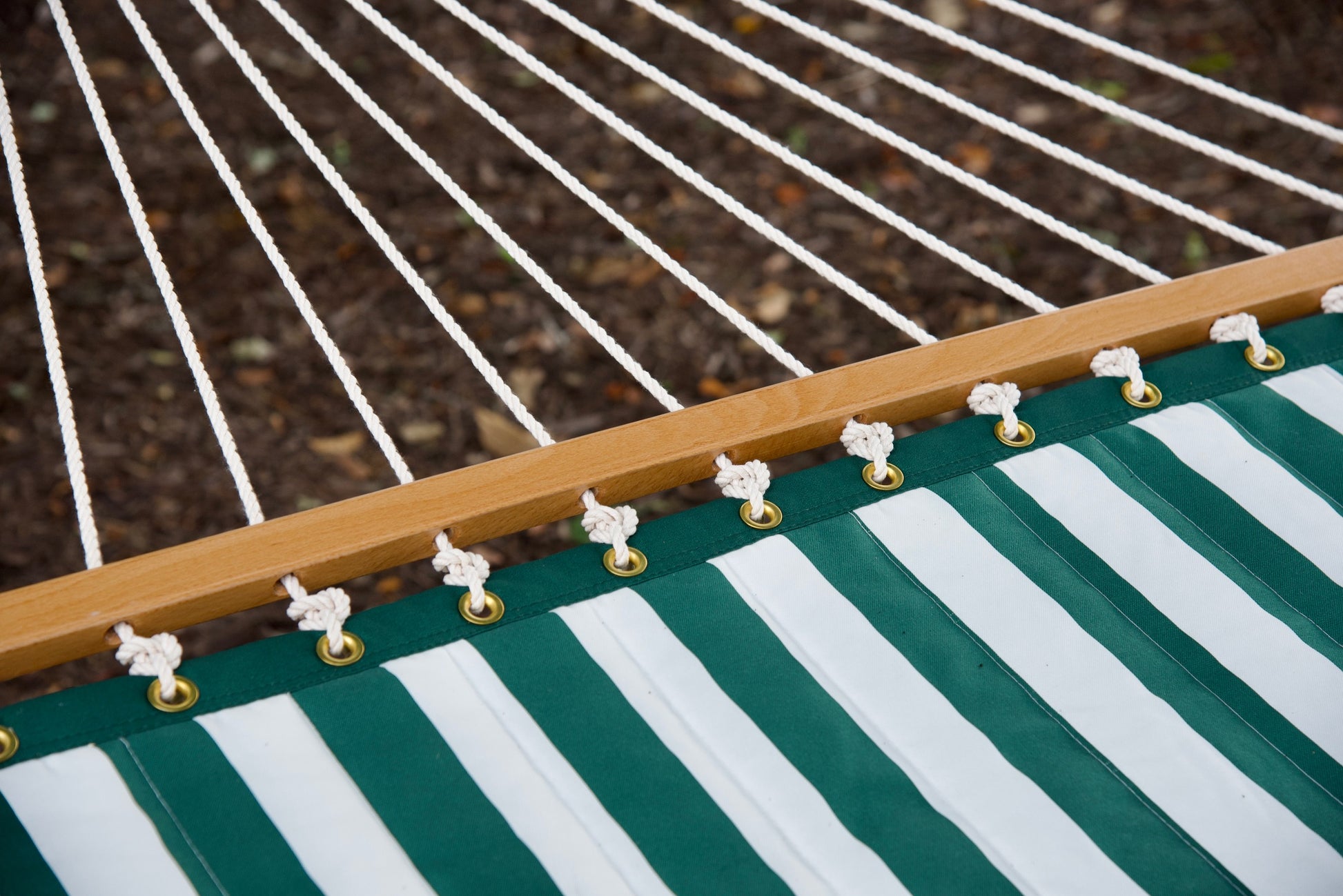 Polyester end cords fanning from the wood spreader bar of a green stripe Island Tranquility hammock