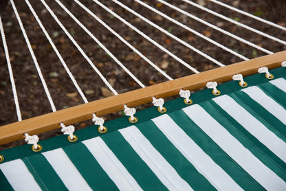 Polyester end cords fanning from the wood spreader bar of a green stripe Island Tranquility hammock