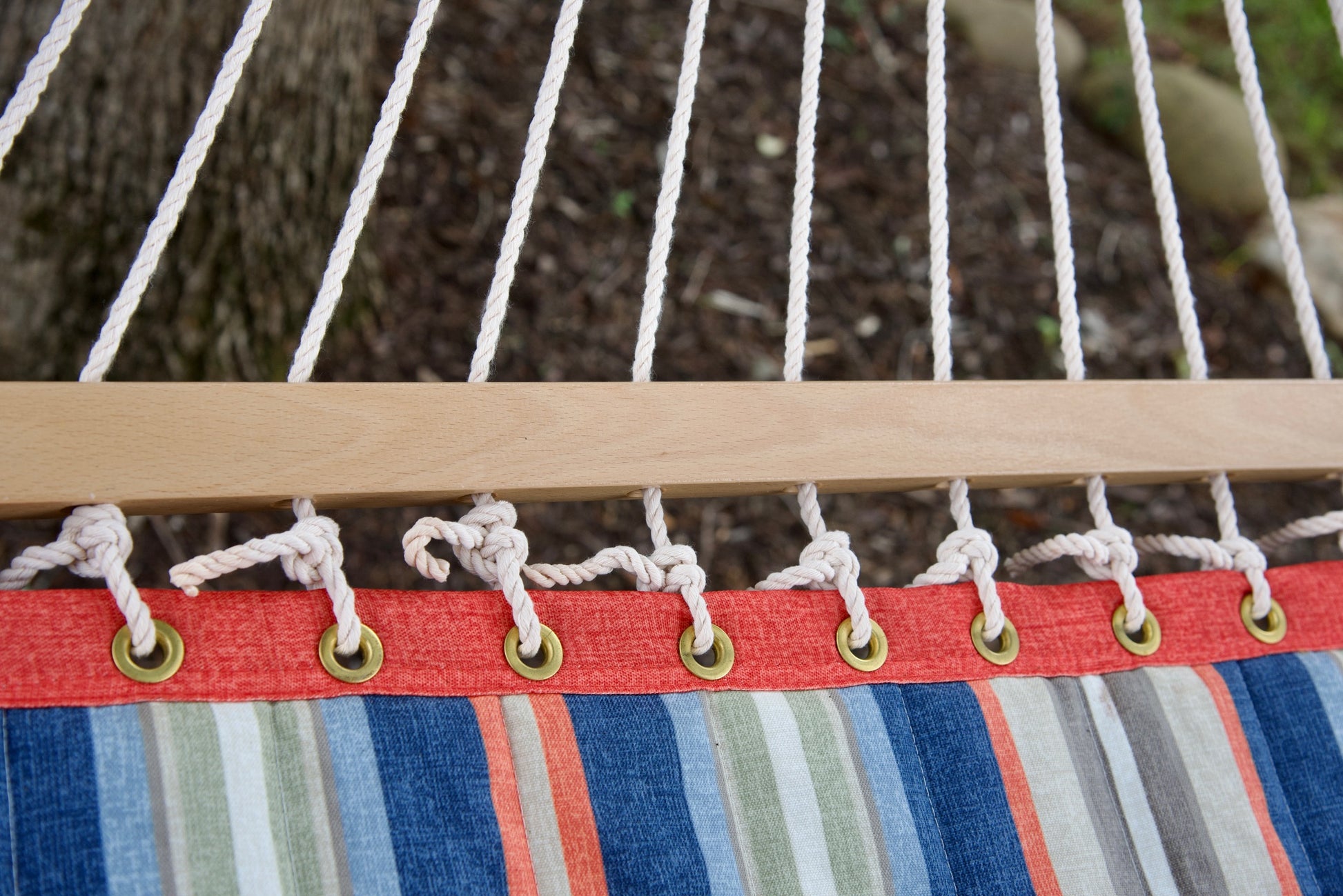Brass roll-rimmed grommets and knotted polyester end cords along the wood spreader bar of a multi Island Tranquility hammock