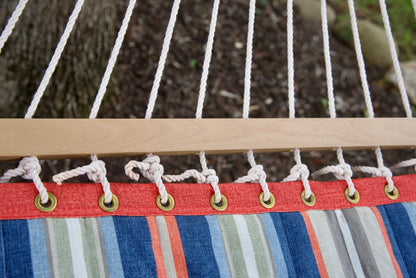 Brass roll-rimmed grommets and knotted polyester end cords along the wood spreader bar of a multi Island Tranquility hammock