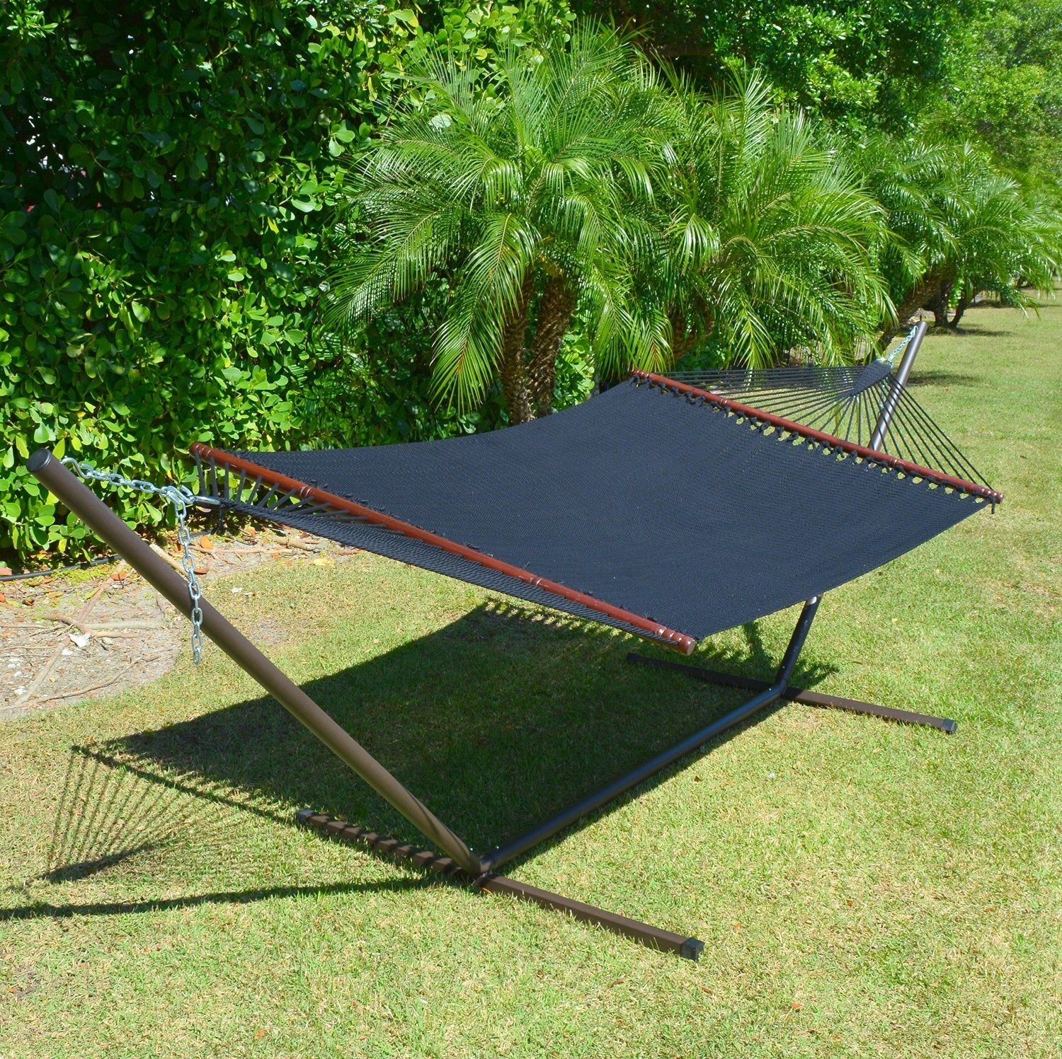 Black Jumbo Caribbean Hammock on a metal Tribeam Hammock Stand in a tropical garden