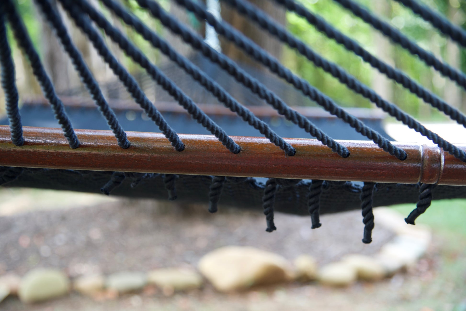 End cords threaded through the drilled hardwood spreader bar of the Black Jumbo Caribbean Hammock