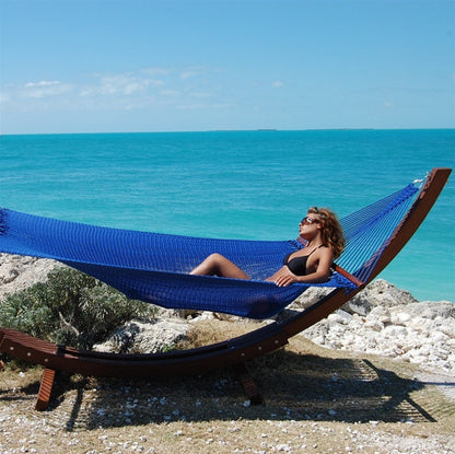 Woman relaxing in the Dark Blue Jumbo Caribbean Hammock on the Wood Arc Hammock Stand