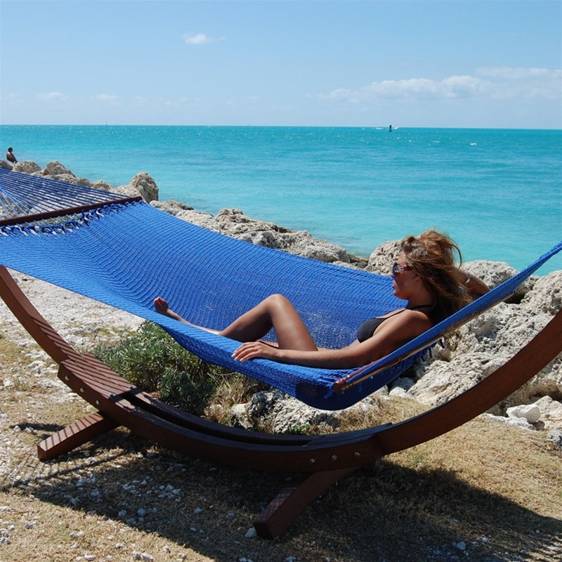 Woman relaxing in the Dark Blue Jumbo Caribbean Hammock on the Wood Arc Hammock Stand