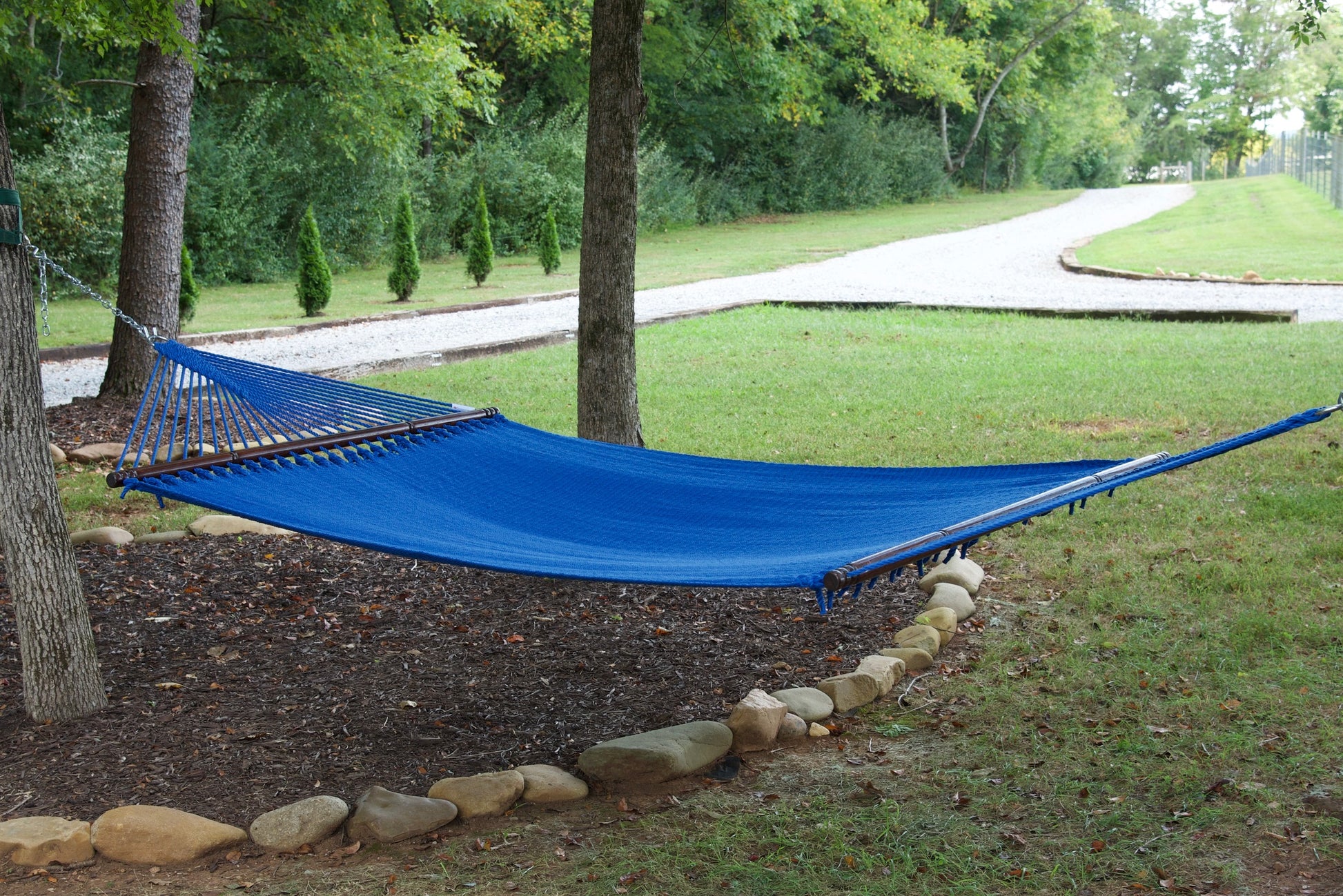 Dark Blue Jumbo Caribbean Hammock hanging between two trees in a backyard