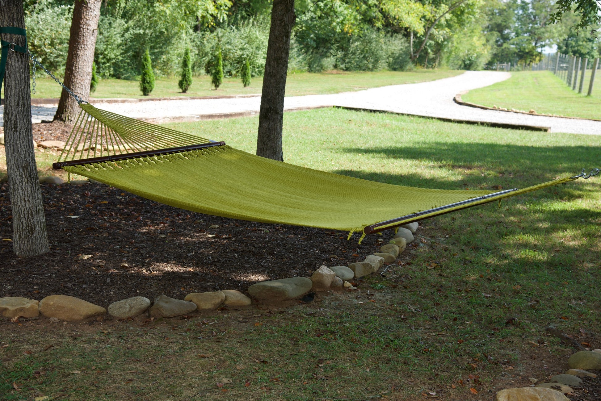 Olive Jumbo Caribbean Hammock hanging between two trees in a backyard
