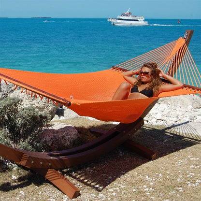 Woman relaxing in the Orange Jumbo Caribbean Hammock on the Wood Arc Hammock Stand