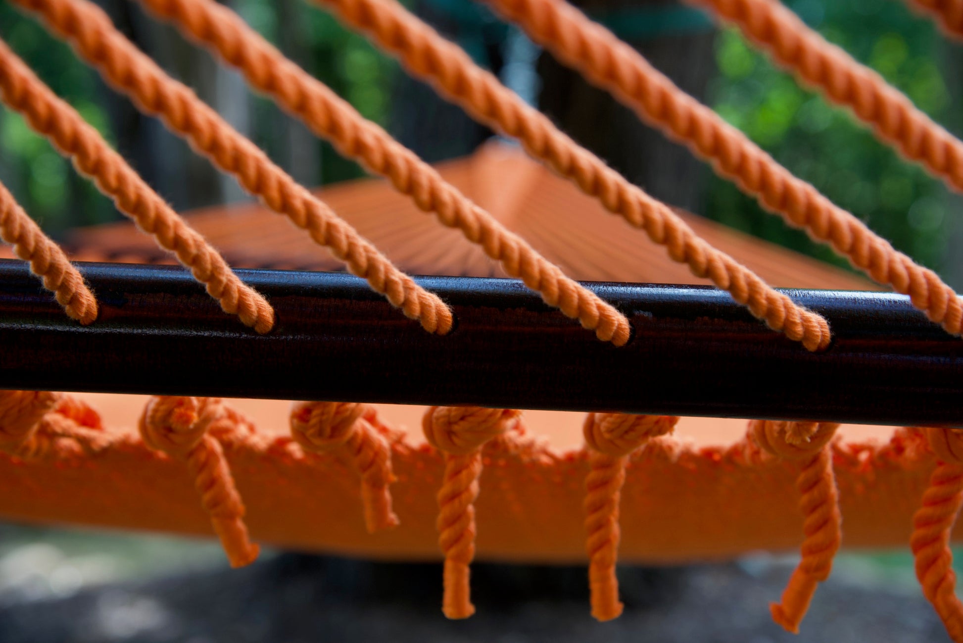 End cords threaded through the drilled hardwood spreader bar of the Orange Jumbo Caribbean Hammock