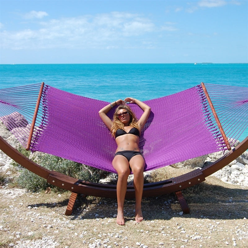 Woman relaxing in the Purple Jumbo Caribbean Hammock on the Wood Arc Hammock Stand