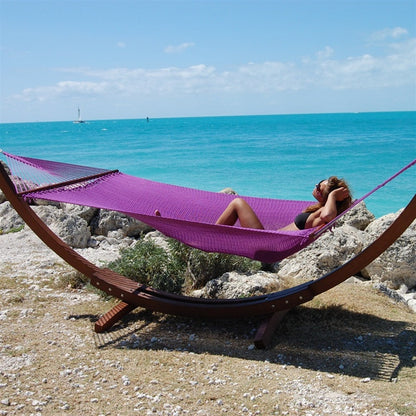 Woman relaxing in the Purple Jumbo Caribbean Hammock on the Wood Arc Hammock Stand