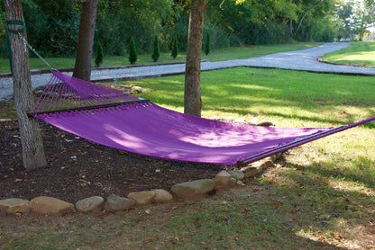 Purple Jumbo Caribbean Hammock hanging between two trees in a backyard