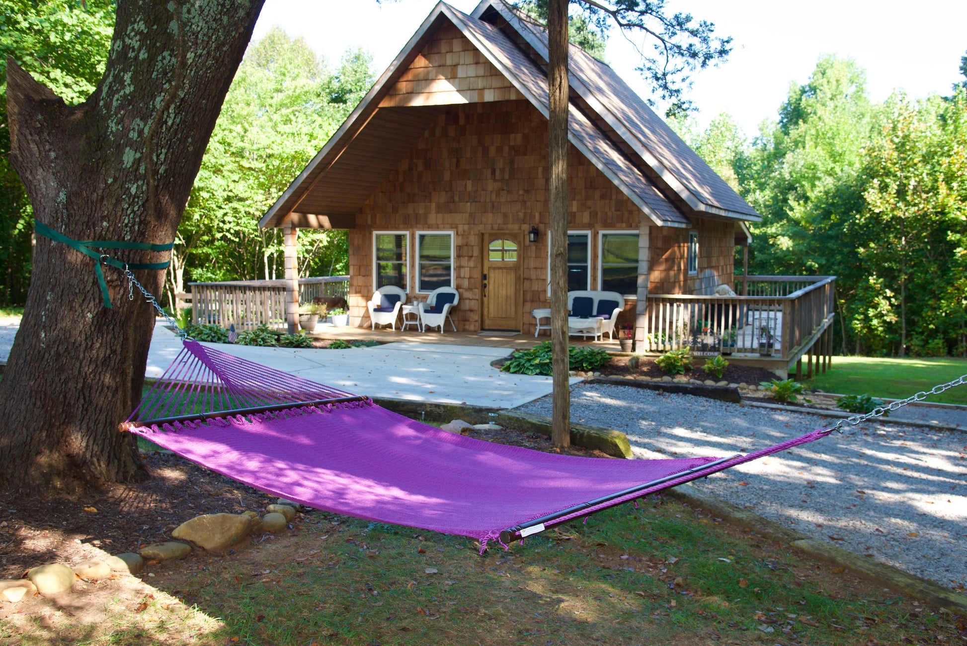 Purple Jumbo Caribbean Hammock strung between two trees in front of a cabin