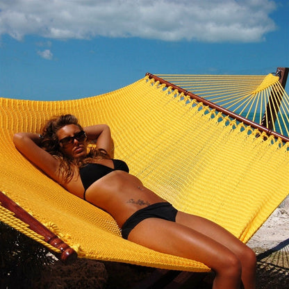 Woman relaxing in the Yellow Jumbo Caribbean Hammock under a blue sky