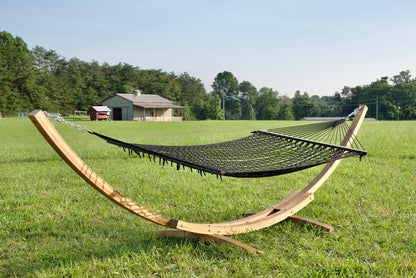 Black Jumbo Rope Hammock hanging on a Wood Arc Hammock Stand in an open grass field.