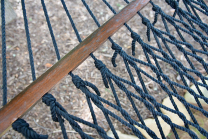 Close view of the varnished wood spreader bar and Black polyester rope of the Jumbo Rope Hammock.