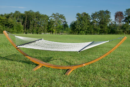 Cream Jumbo Rope Hammock hanging on a Wood Arc Hammock Stand in an open grass field.