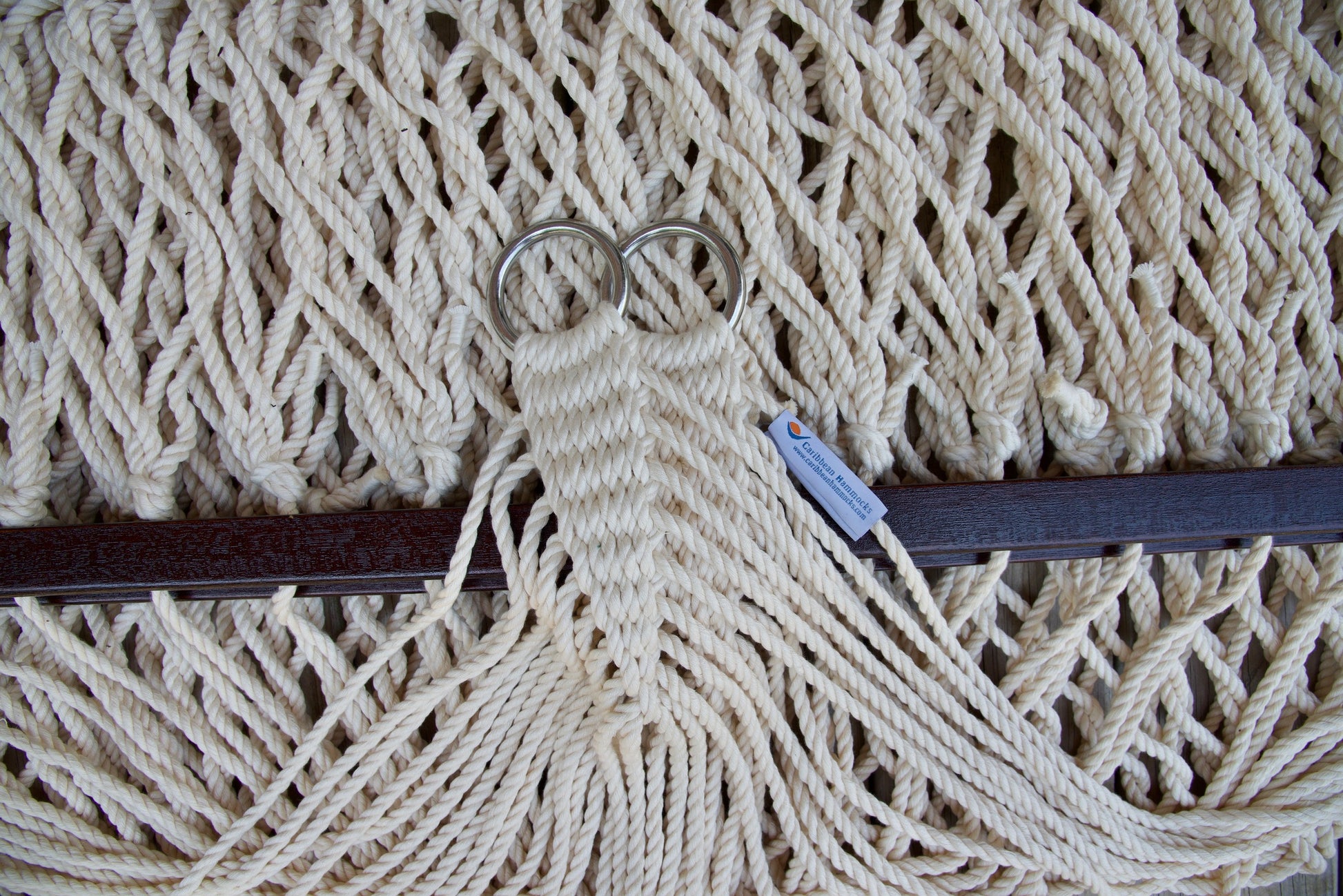 Close view of the gathered Cream end cords and O-rings of the Jumbo Rope Hammock above the wood spreader bar.