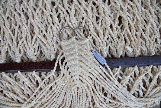 Close view of the gathered Cream end cords and O-rings of the Jumbo Rope Hammock above the wood spreader bar.