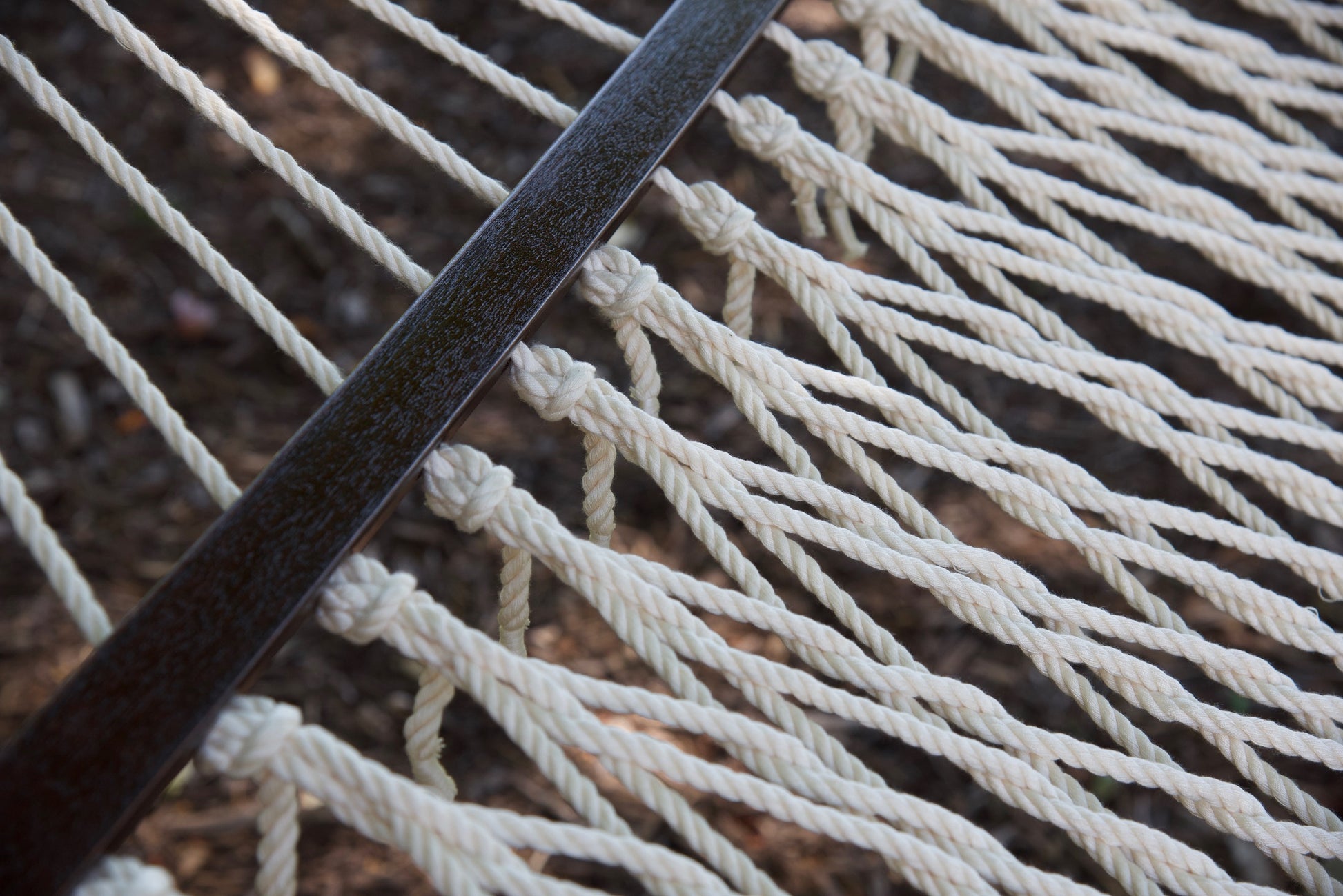 Close view of the varnished wood spreader bar and Cream polyester rope of the Jumbo Rope Hammock.