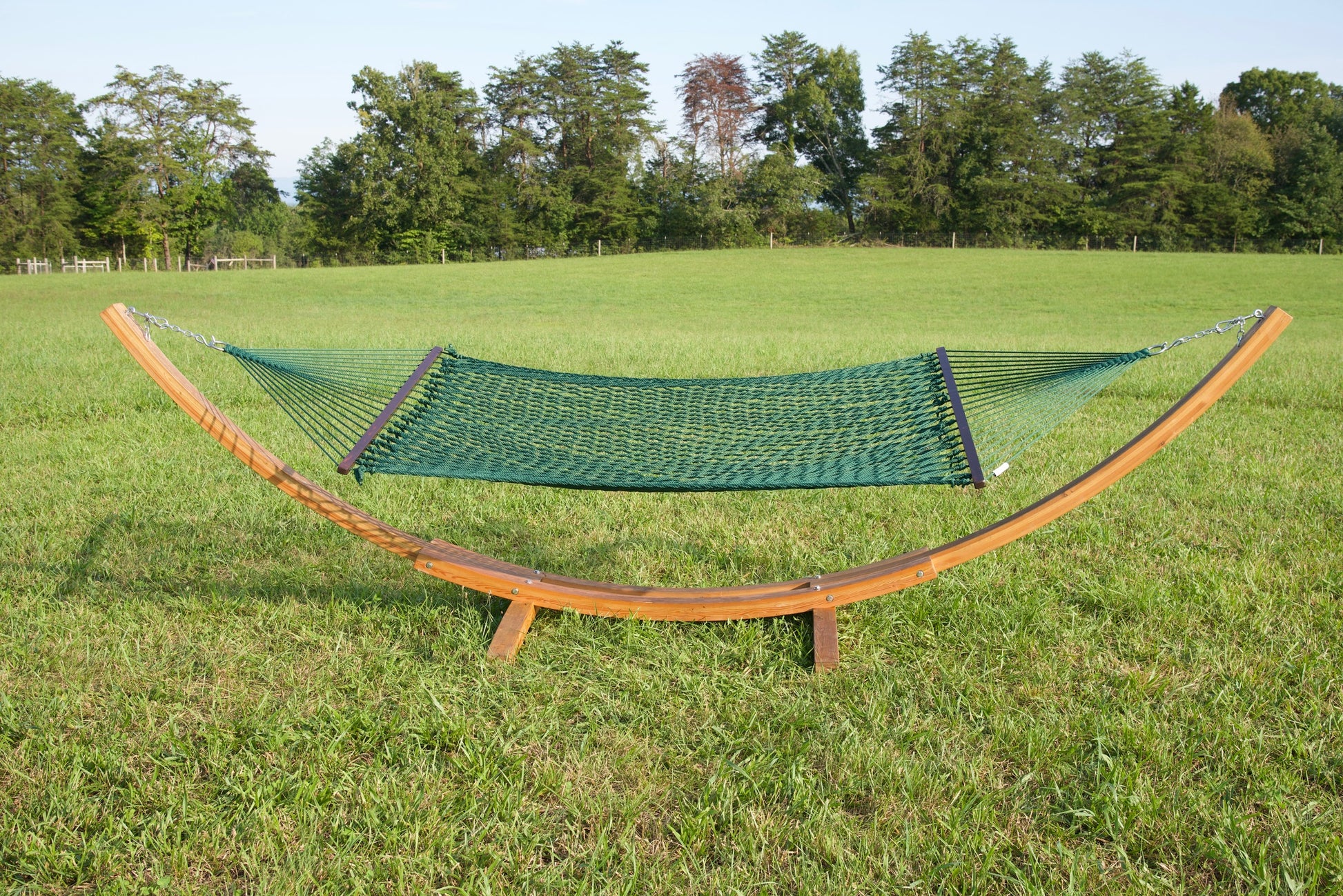 Green Jumbo Rope Hammock hanging on a Wood Arc Hammock Stand in an open grass field.