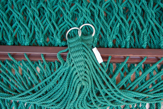 Close view of the gathered Green end cords and O-rings of the Jumbo Rope Hammock above the wood spreader bar.