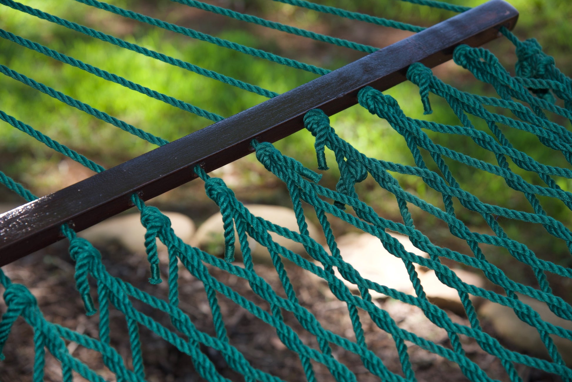 Close view of the varnished wood spreader bar and Green polyester rope of the Jumbo Rope Hammock.