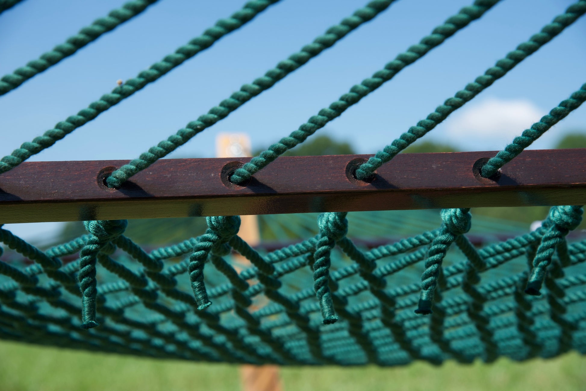 Close view of the Green end cords threaded through the wood spreader bar of the Jumbo Rope Hammock.