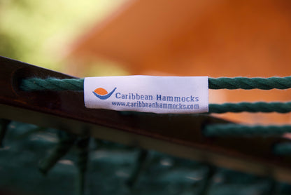 Caribbean Hammocks brand label wrapped around a Green end cord of the Jumbo Rope Hammock, beside the solid hardwood spreader bar.