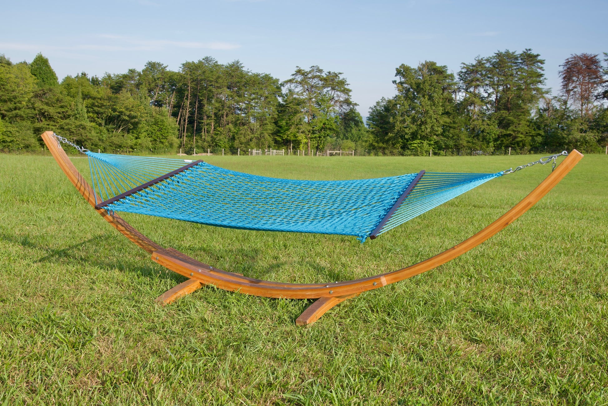 Light Blue Jumbo Rope Hammock hanging on a Wood Arc Hammock Stand in an open grass field.