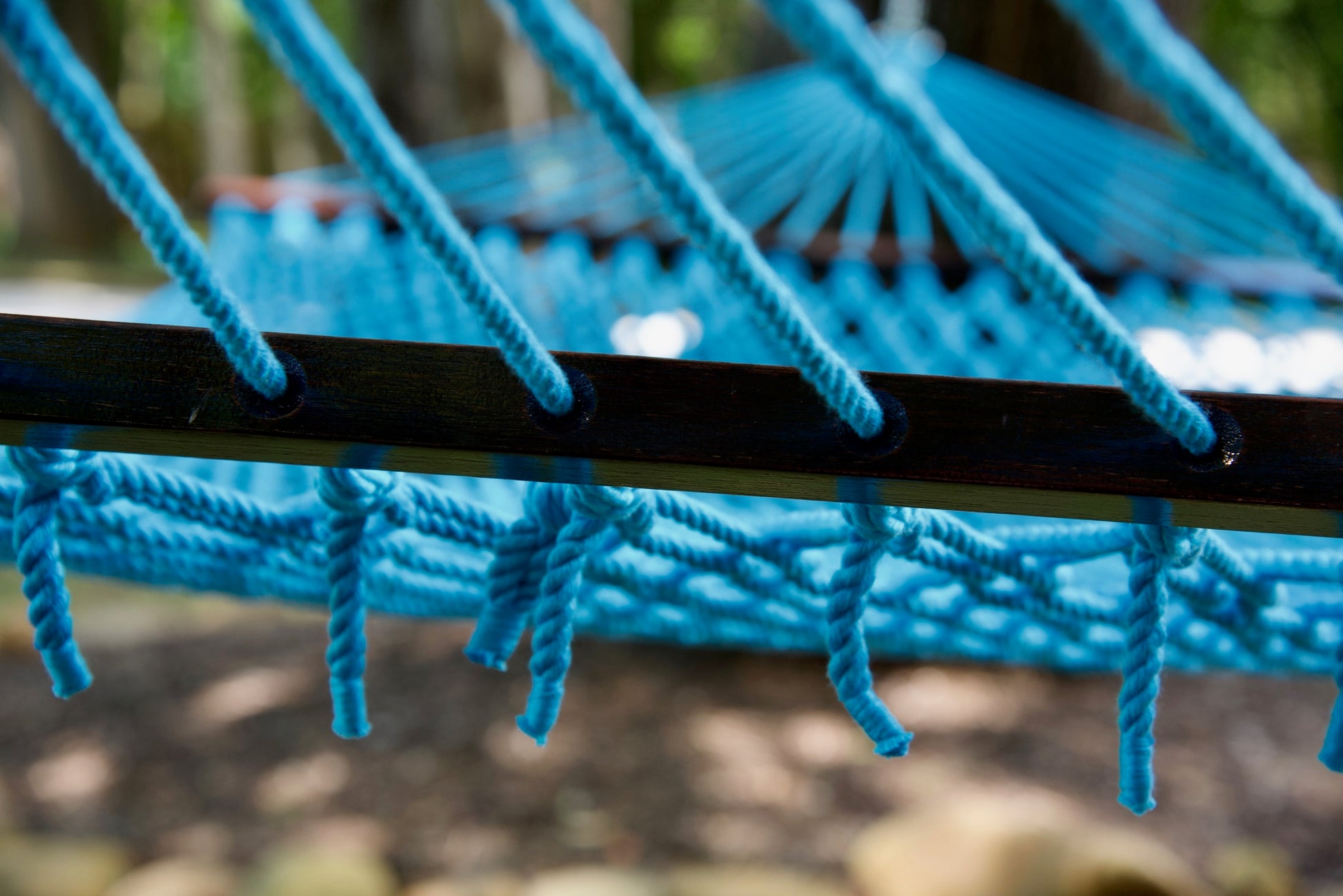 Close view of the Light Blue end cords threaded through the wood spreader bar of the Jumbo Rope Hammock.