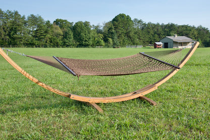 Mocha Jumbo Rope Hammock hanging on a Wood Arc Hammock Stand in an open grass field.