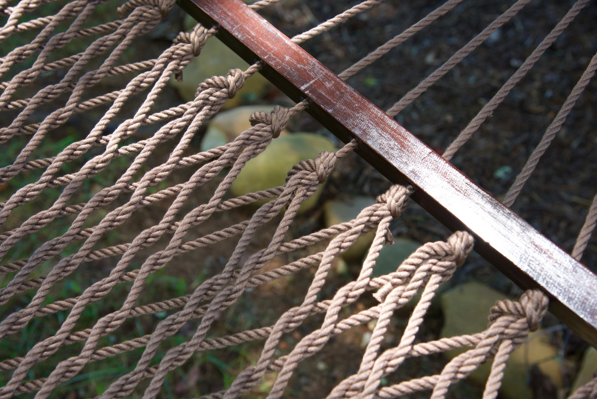 Close view of the varnished wood spreader bar and Mocha polyester rope of the Jumbo Rope Hammock.