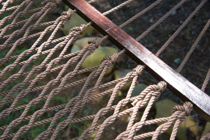 Close view of the varnished wood spreader bar and Mocha polyester rope of the Jumbo Rope Hammock.