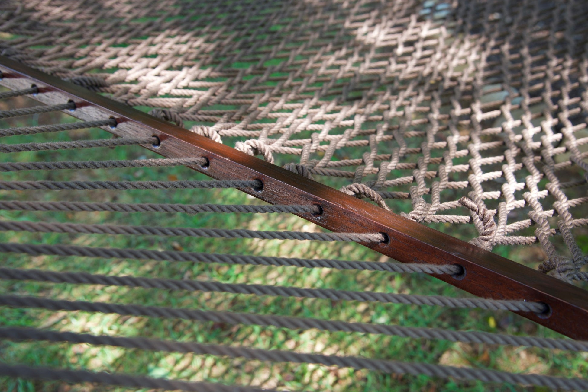 Close view of the varnished wood spreader bar and Mocha polyester rope of the Jumbo Rope Hammock.
