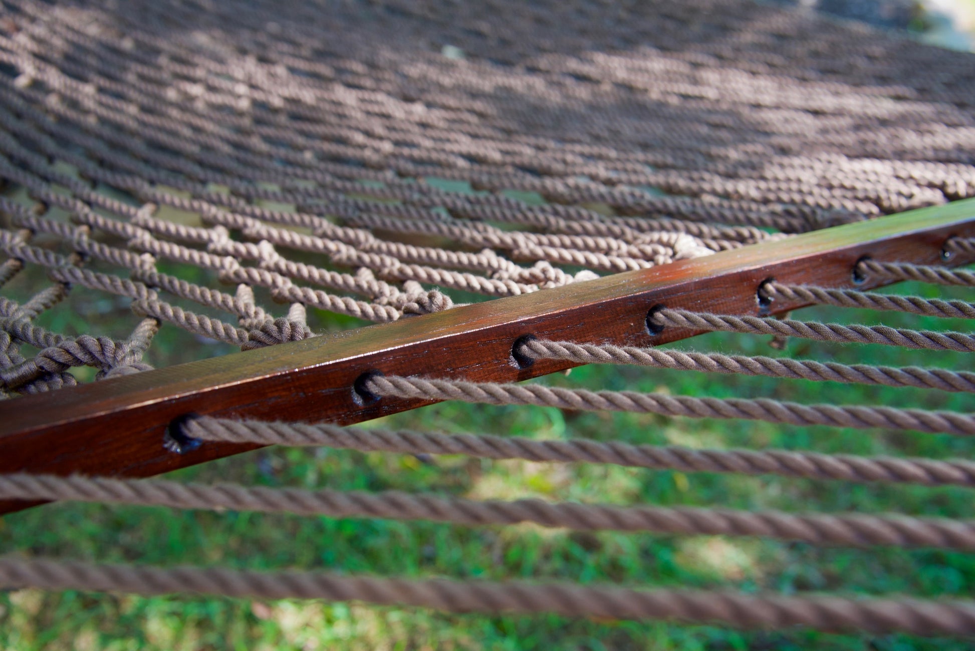 Close view of the Mocha end cords threaded through the wood spreader bar of the Jumbo Rope Hammock.
