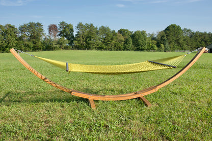 Olive Jumbo Rope Hammock hanging on a Wood Arc Hammock Stand in an open grass field.
