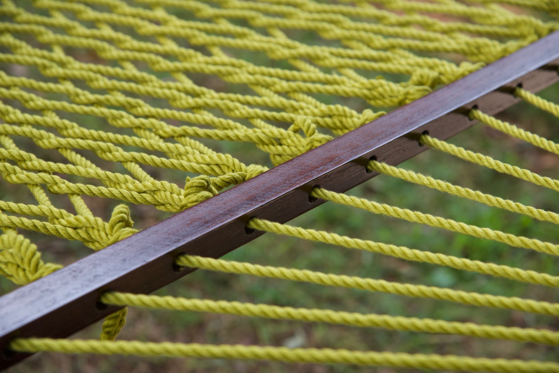 Close view of the varnished wood spreader bar and Olive polyester rope of the Jumbo Rope Hammock.