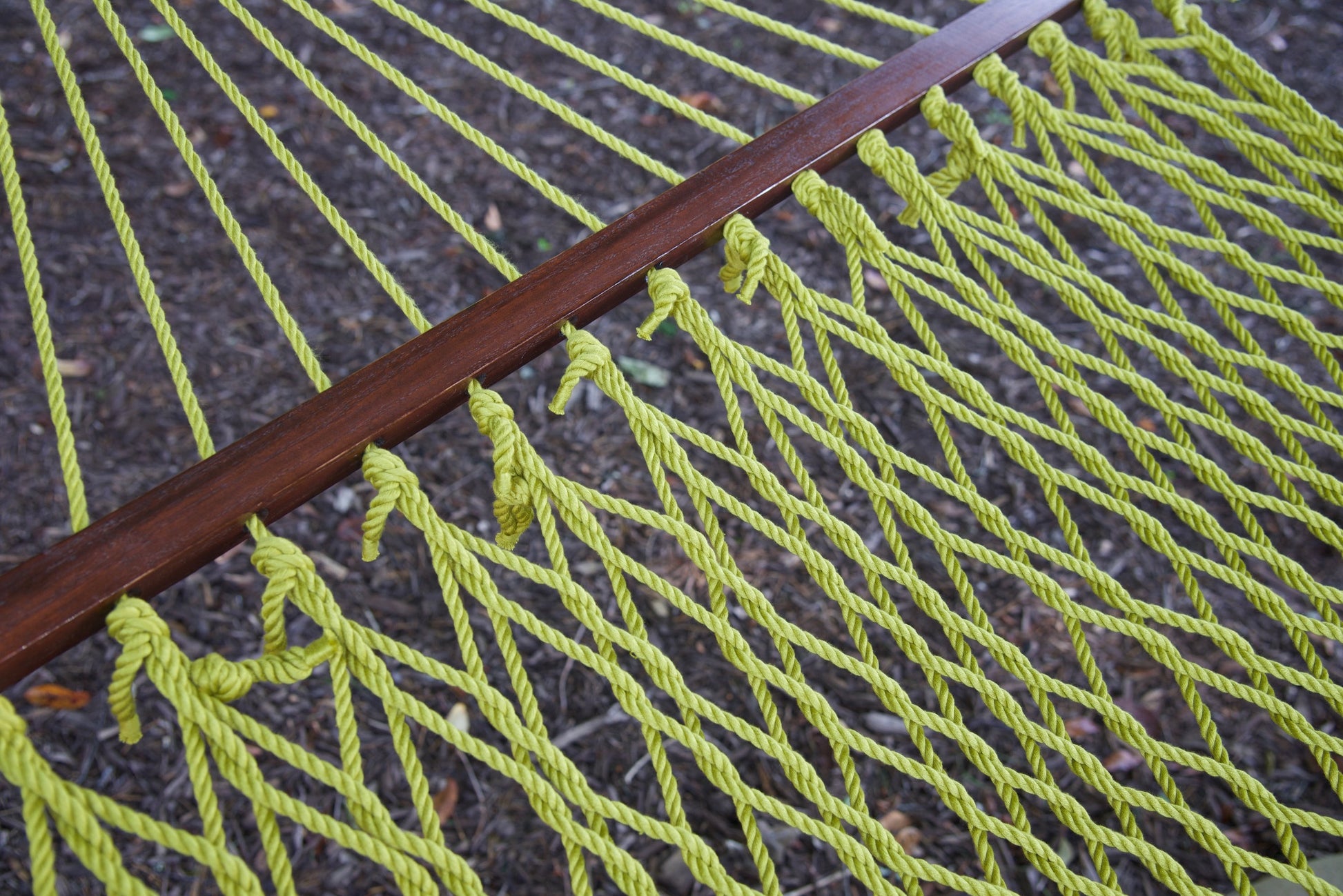 Close view of the Olive end cords threaded through the wood spreader bar of the Jumbo Rope Hammock.